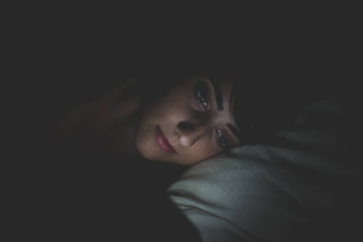 Close-up of a woman lying awake in bed at night, suggesting insomnia or a 3 a.m. wake-up.