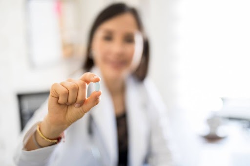 Doctor holding an HRT pill during a women’s hormone replacement therapy consultation.