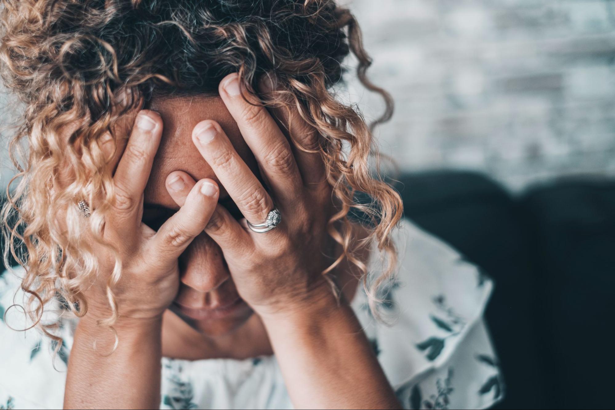 Woman holding her head in distress, illustrating emotional strain and prolonged stress impacting mental and physical health.