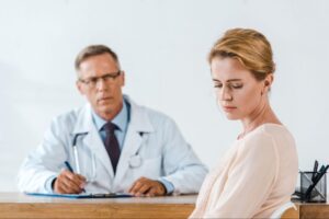 Woman appearing distressed during a medical consultation with a doctor, representing concerns about menopause symptoms and feeling dismissed in healthcare.