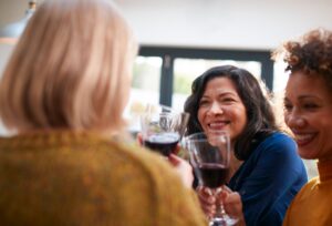 A group of mature women enjoying a glass of wine together, symbolizing socializing and the discussion around alcohol consumption during menopause.