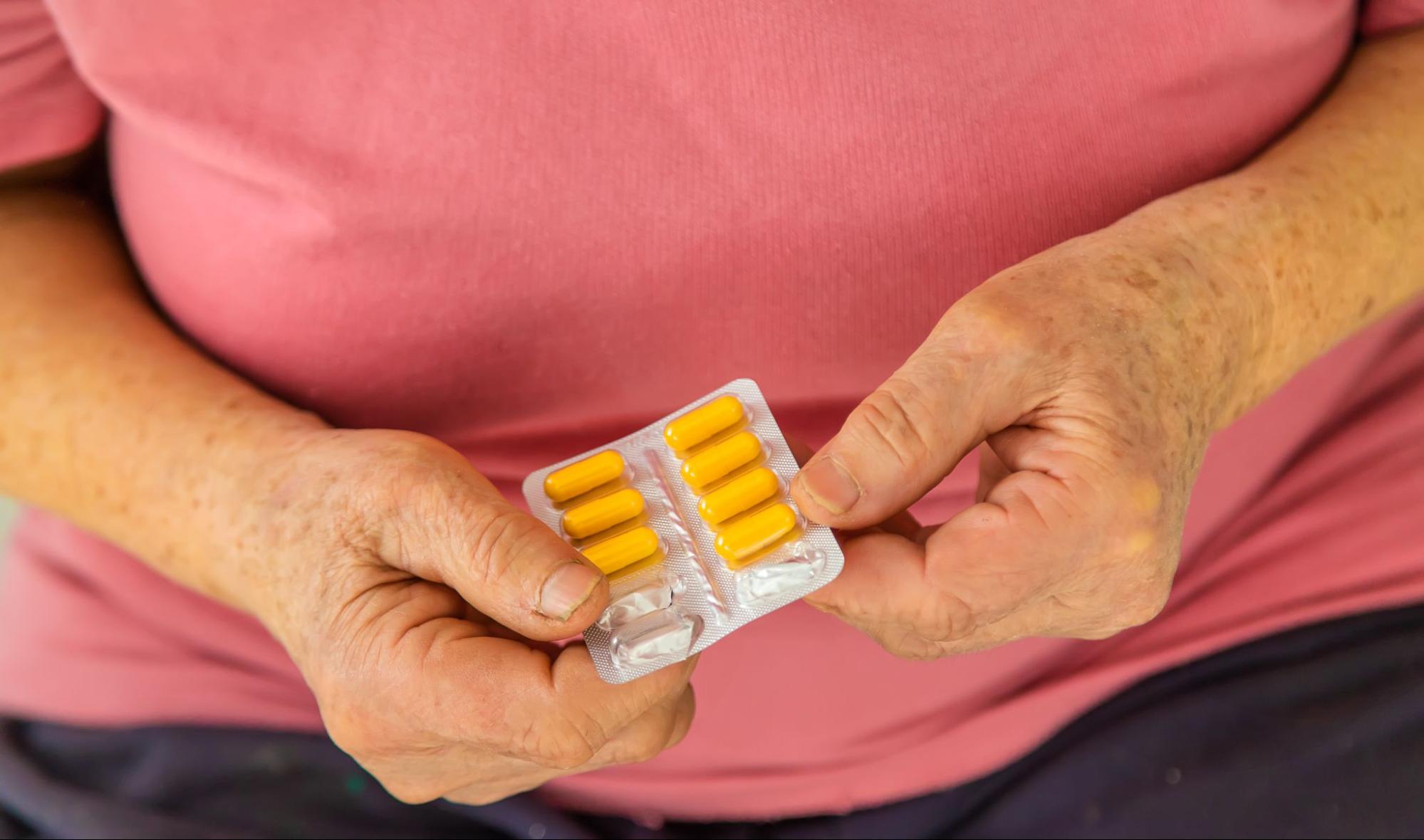 Woman holding medication for weight loss during menopause, representing GLP-1 treatment options.